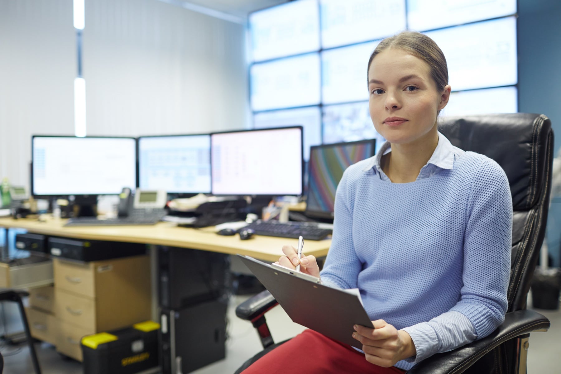Professional sitting in an office with multiple screens while reviewing notes